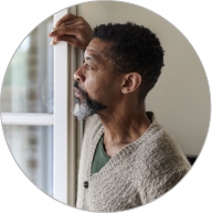 Side view of a man leaning against a wall while looking out the window